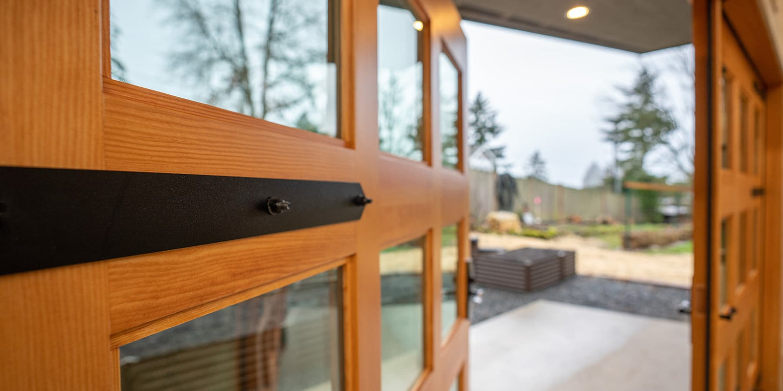 Custom Douglas Fir Carriage Doors for McIntyre Furniture. Image highlights door details: glass panes, wood grain patter, and strap hinges.