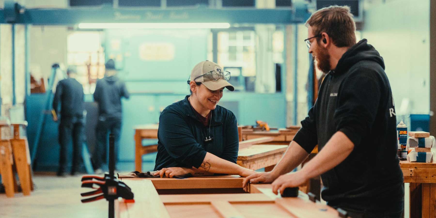 Craftsman and Craftswoman building a door and laughing 