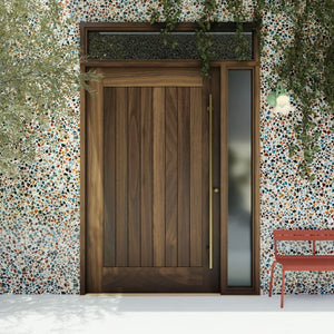Monterey Single Panel Tongue and Groove Pivot Door with sidelights and transom and a long brass handle in a colorful garden wall