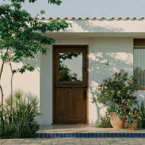 White house with a wooden dutch door and potted plants on a sunny day