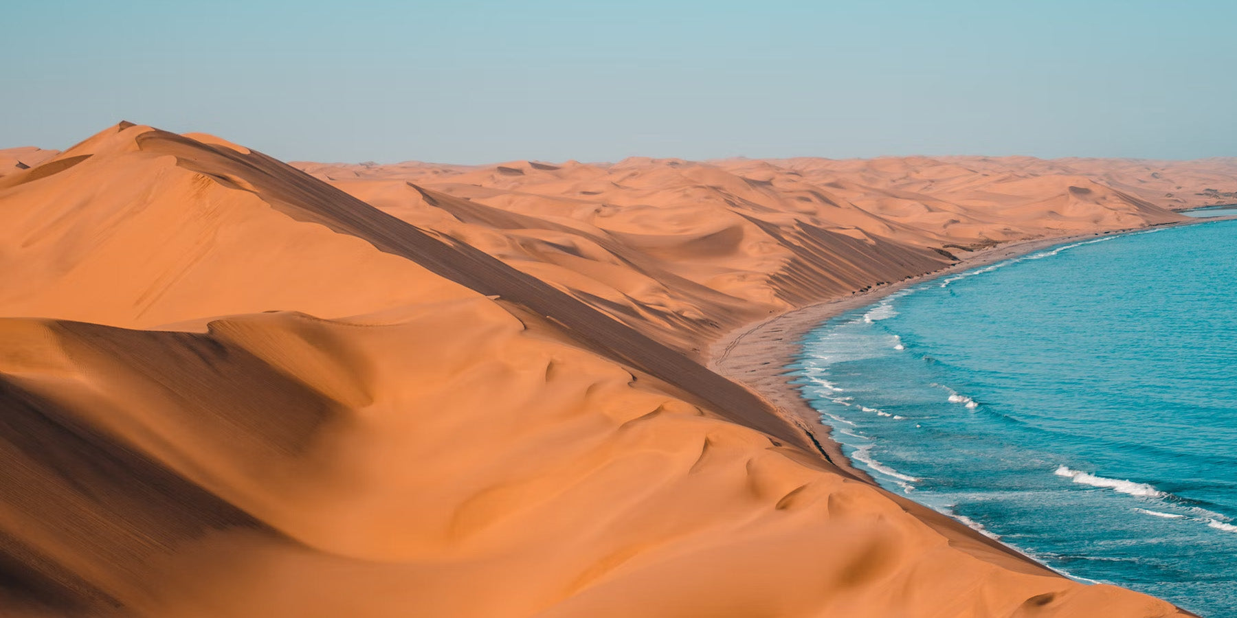 Desert with sand dunes and blue ocean