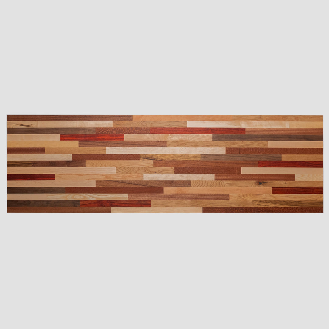 A long, horizontal wood countertop wall art piece made of various solid colors and patterns in reds, browns, yellows, and other earth tones. The background is white with no shadows or textures on it. This artwork would be used as an accent for the dining room table, sitting under that wall art, and to match its color scheme.