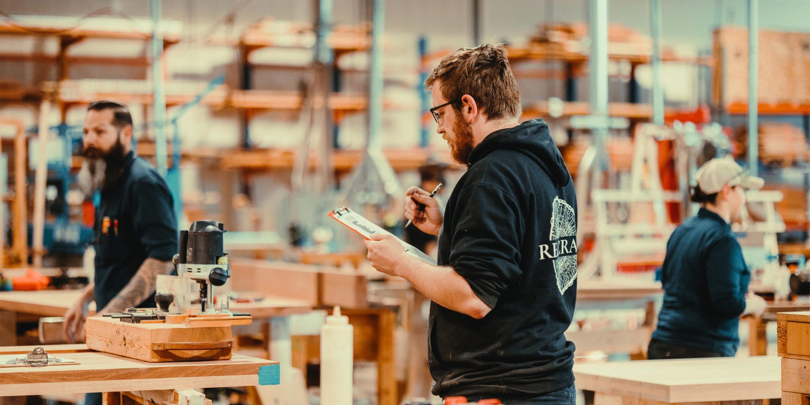 Craftsman holding a clipboard at the woodshop.