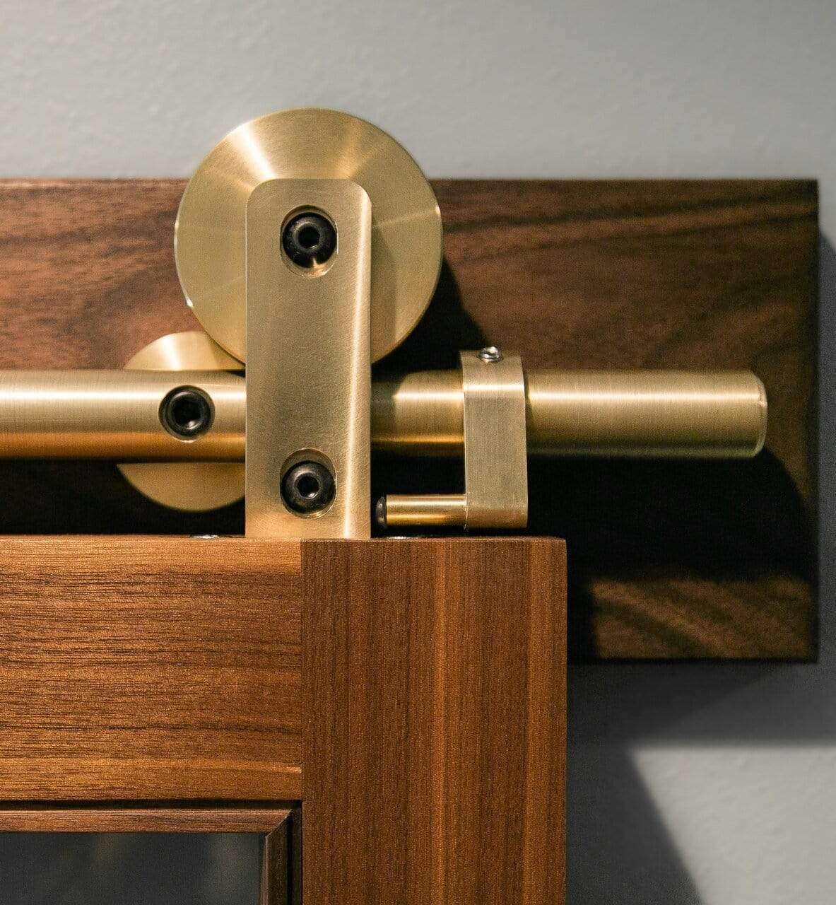 Solid Brass Swiss Rod Barn Door Hardware installed on a Sapele mahogany wood header board