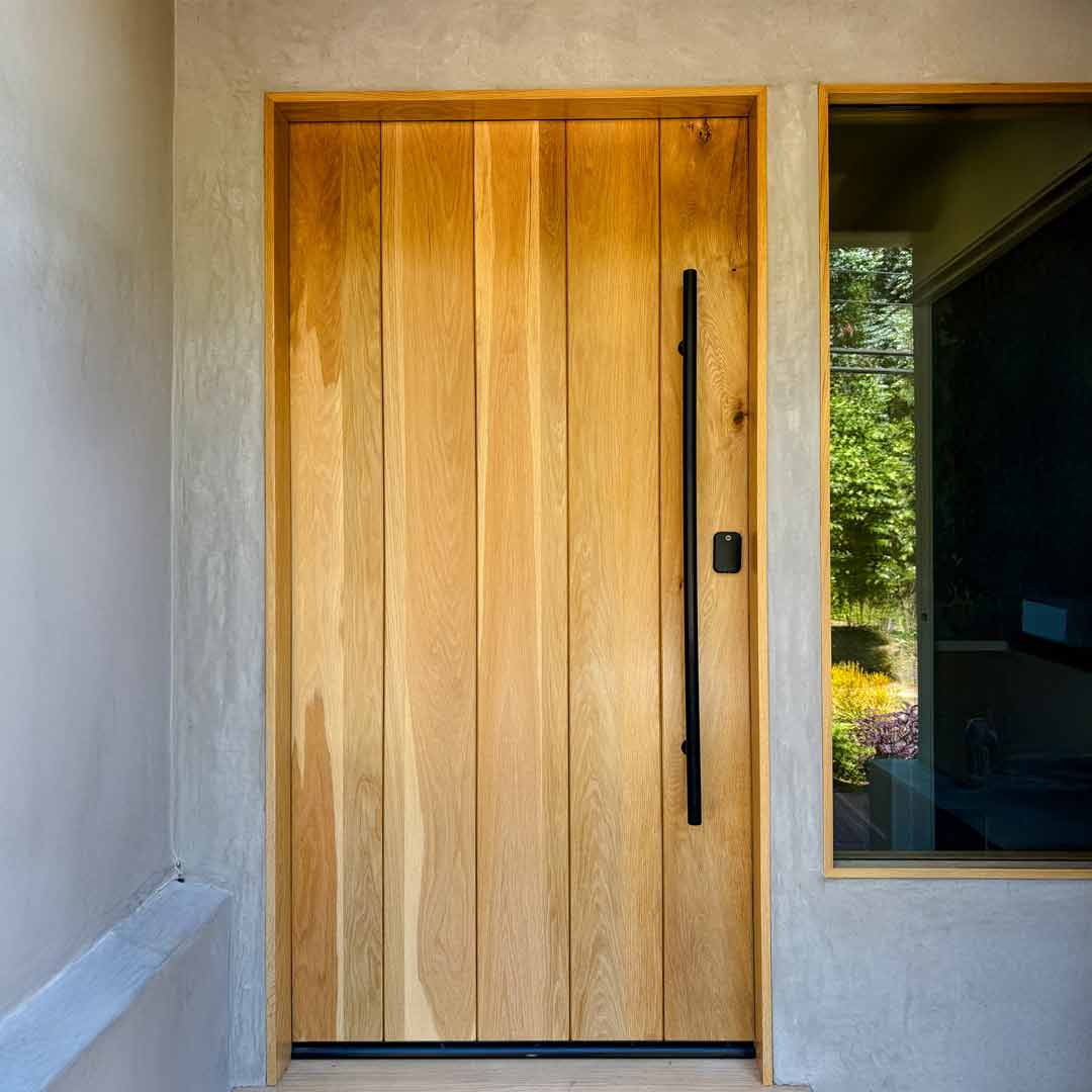 Wooden front door with a black handle on a house exterior.