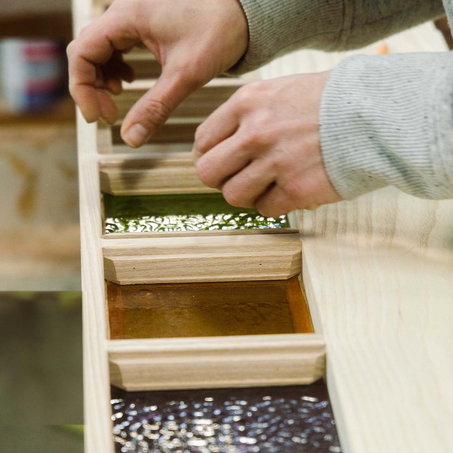 Craftswoman inserting colored stained glass panes on a custom entry door