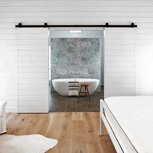 Double white sliding barn doors opening to a bathroom