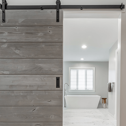 weathered door gray barn door installed in a bathroom space