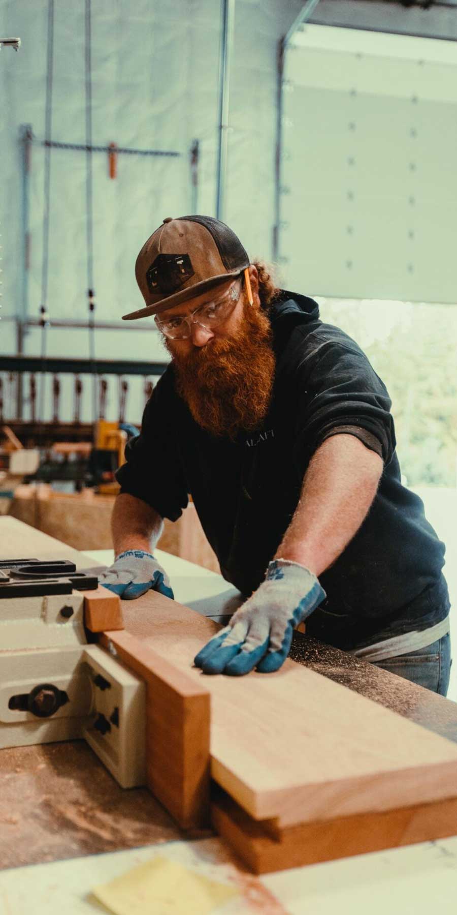 Craftsman with a long beard working on a wood cutting machine.