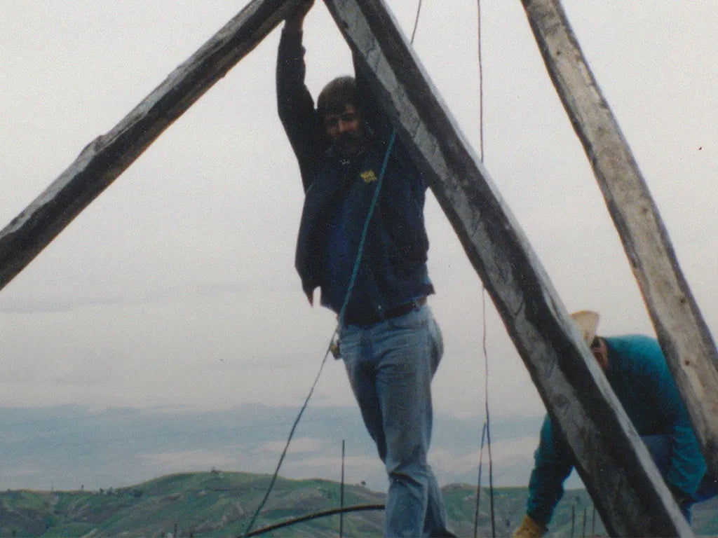 A man in the mountains area holding up wooden beams