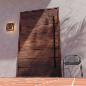 Walnut Wood Pacifica Contemporary Pivot Door on a modern entryway with concrete wall and red tiles next to a chair and a modern wood wall lamp