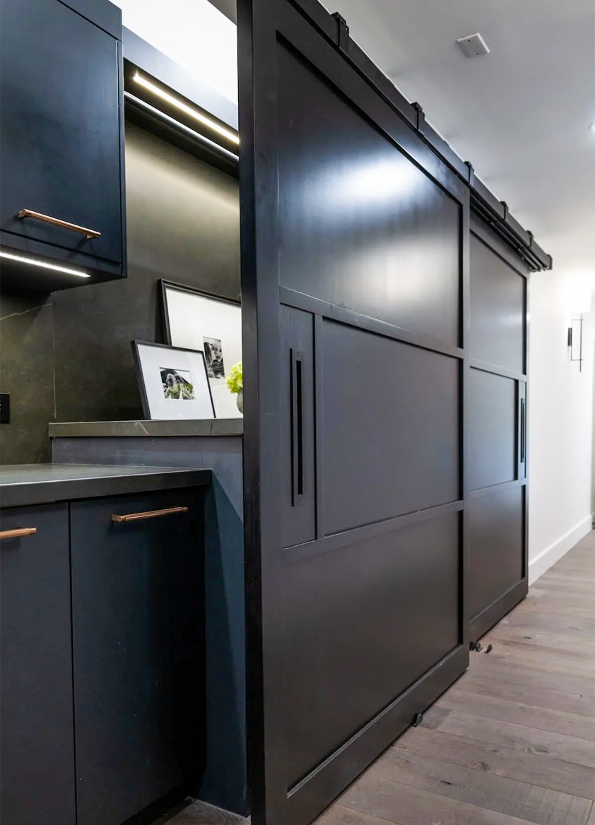 Custom Black barn doors and box rail hardware in a luxury laundry room