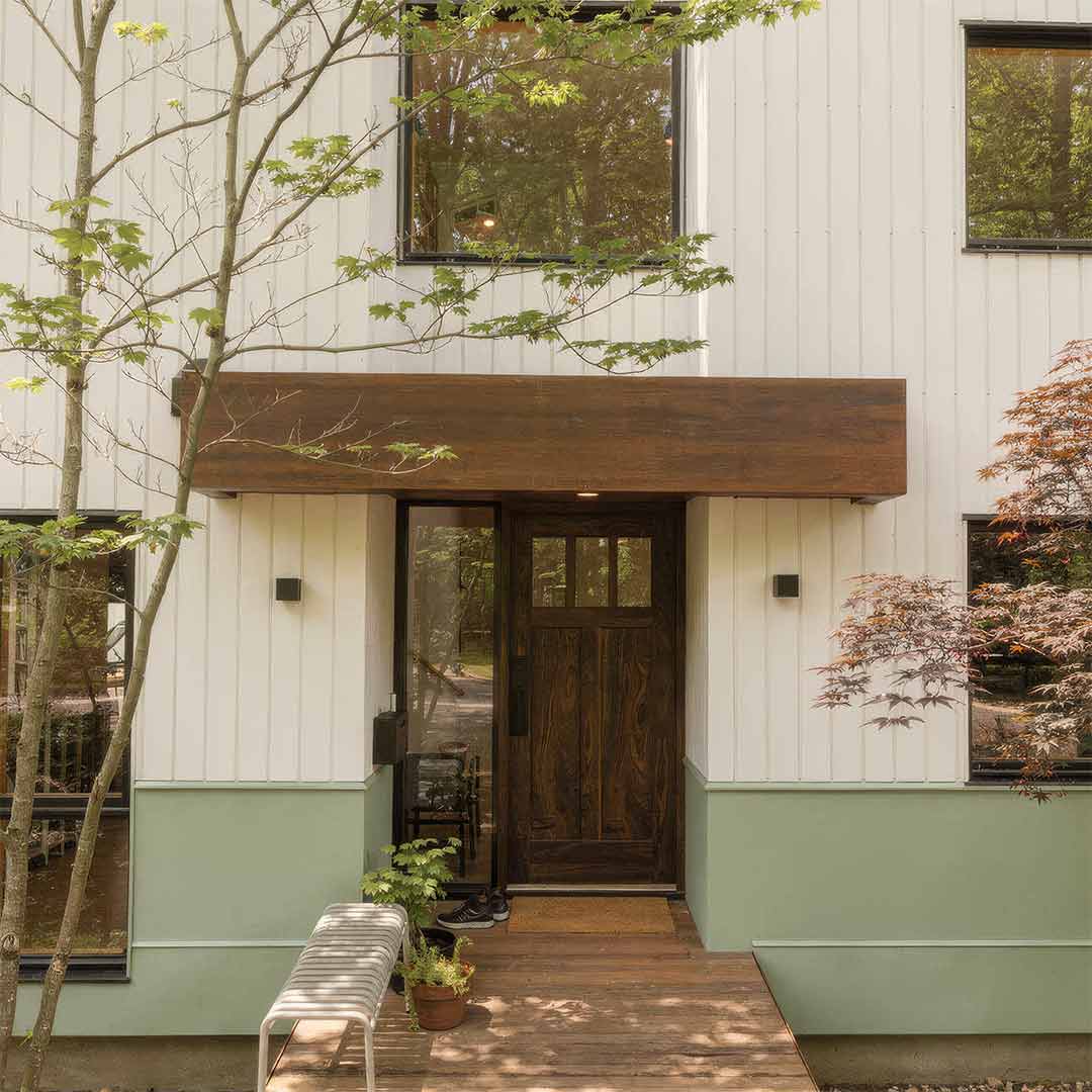 Modern house exterior with a wooden walnut front door and green base