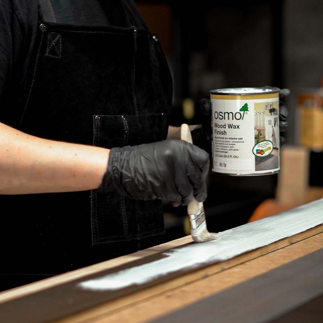 Hands applying Osmo wood finish on a cedar wood plank