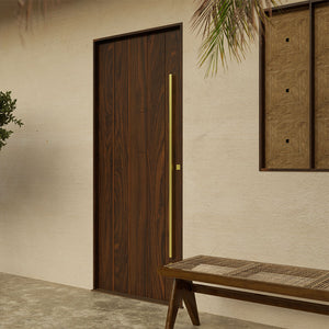 Custom modern walnut entry door featuring vertical planks and minimalist brass handle, designed for luxury curb appeal.