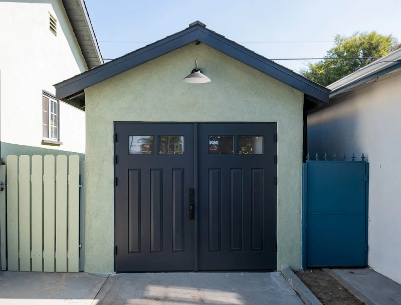 Two garage carriage doors with a black door pull