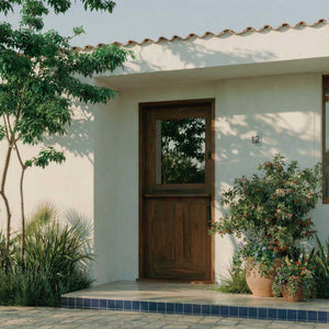 White house exterior with a walnut wood dutch door and potted plants