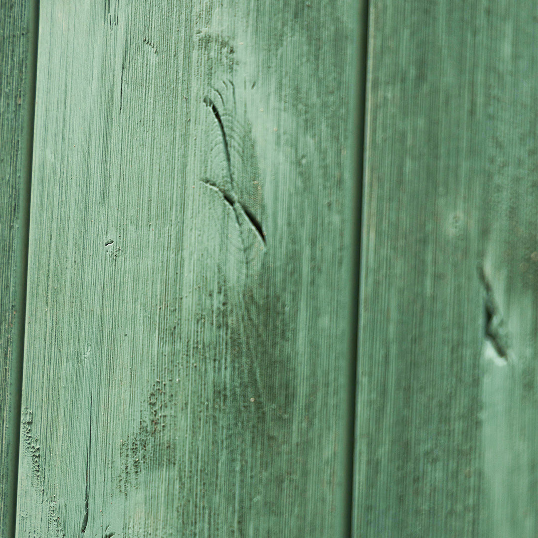 Close up shot of a weathered wood barn door in green