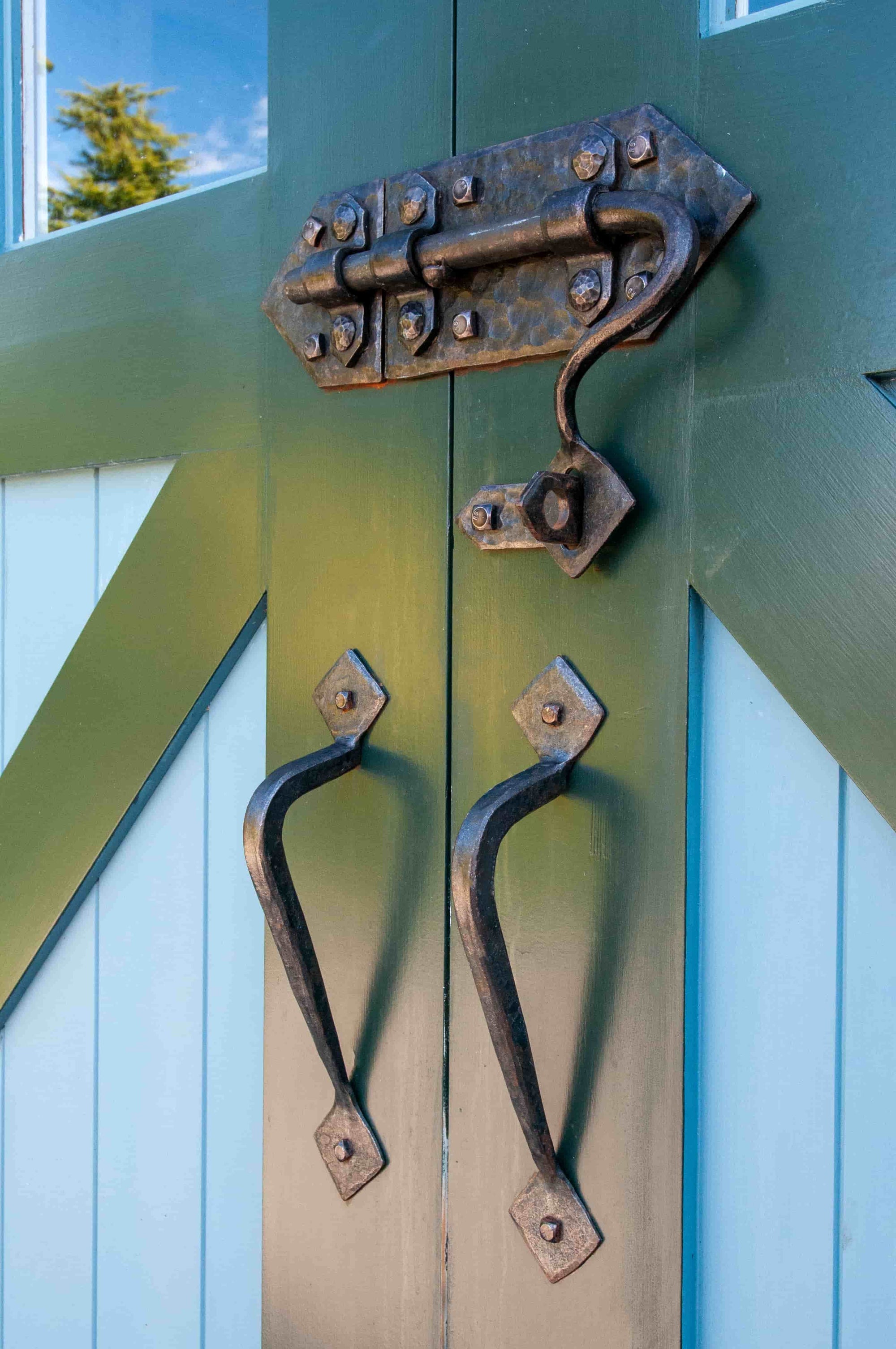 Hand-forged door hardware installed green carriage door