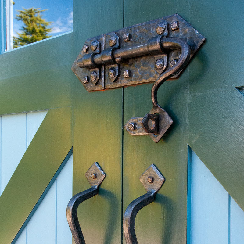 hand-forged door hardware on green garage doors