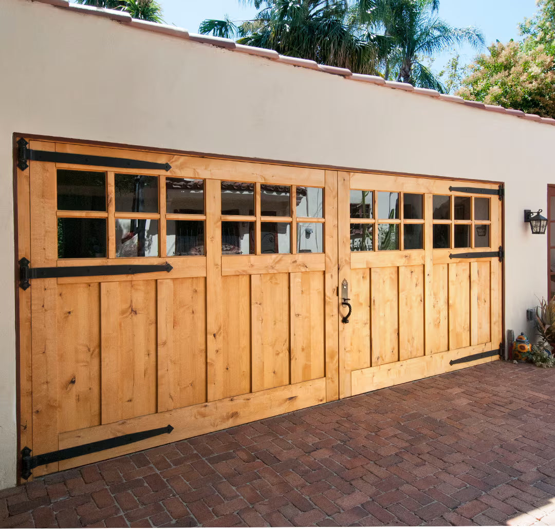 Extra-large traditional carriage garage door with twelve clear glass window panels and large decorative hinges, shown on a residential exterior in daylight.