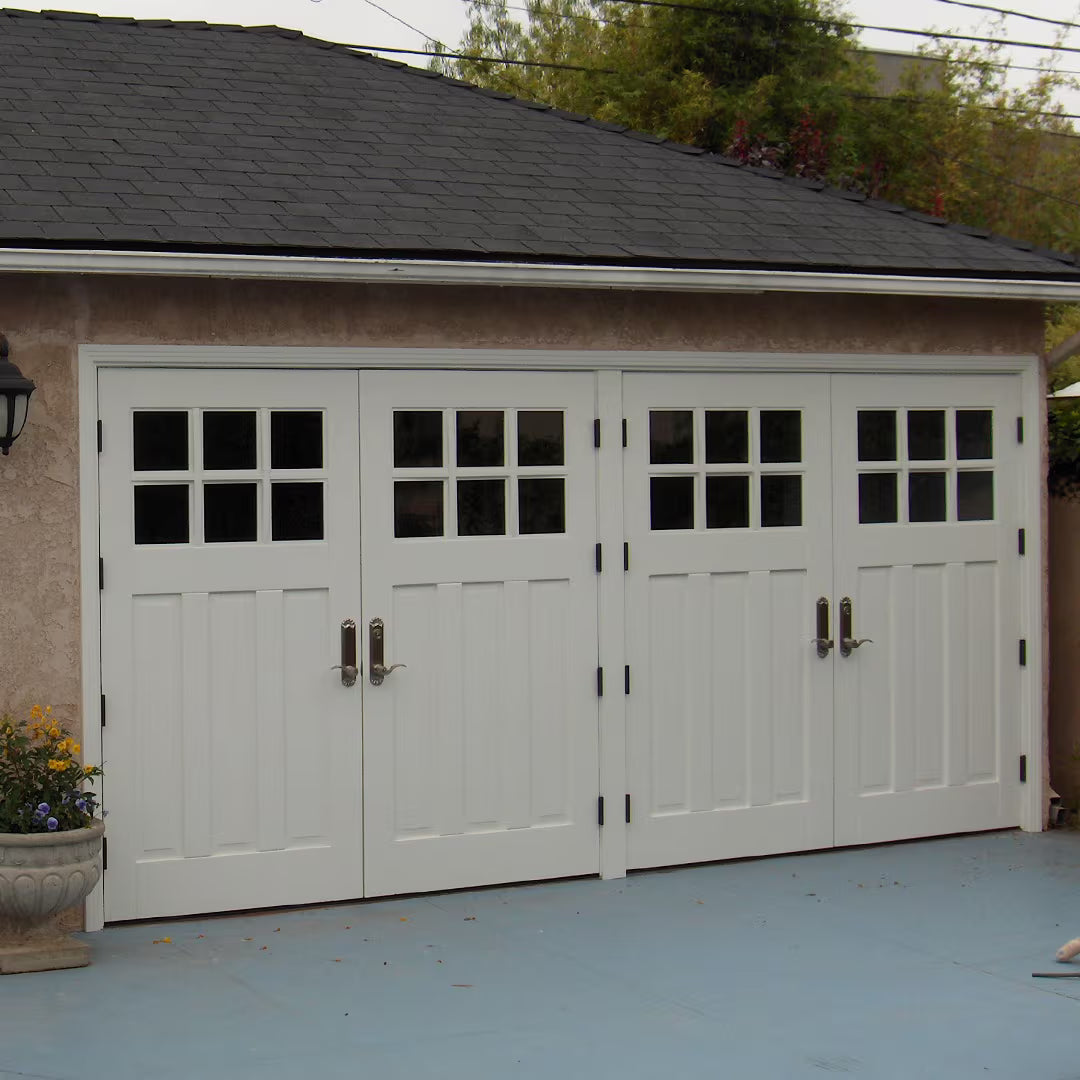 White Craftsman-style carriage garage door with small decorative hinges, shown on a residential exterior in natural daylight.