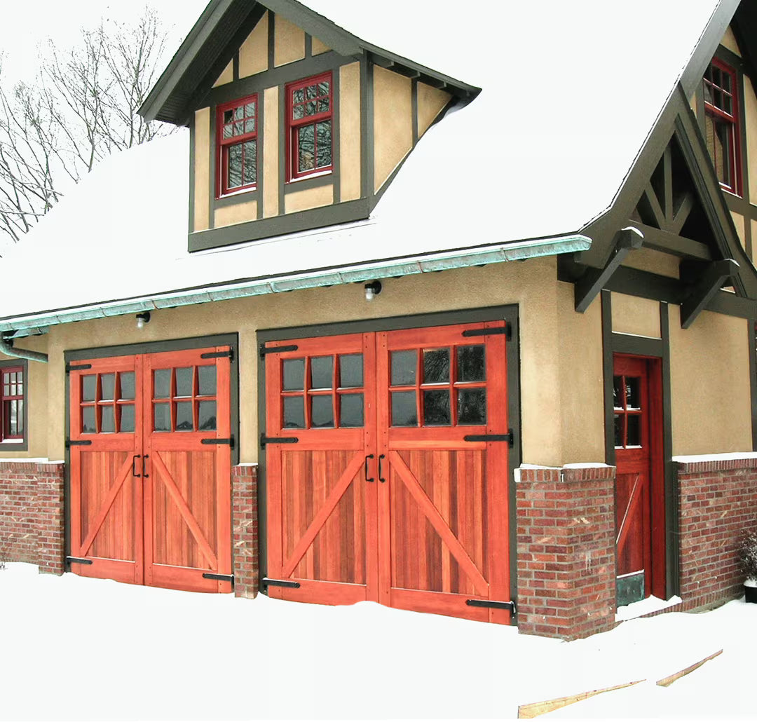 Redwood-toned Z-brace carriage garage door with strap hinges, shown on a residential exterior in daylight.
