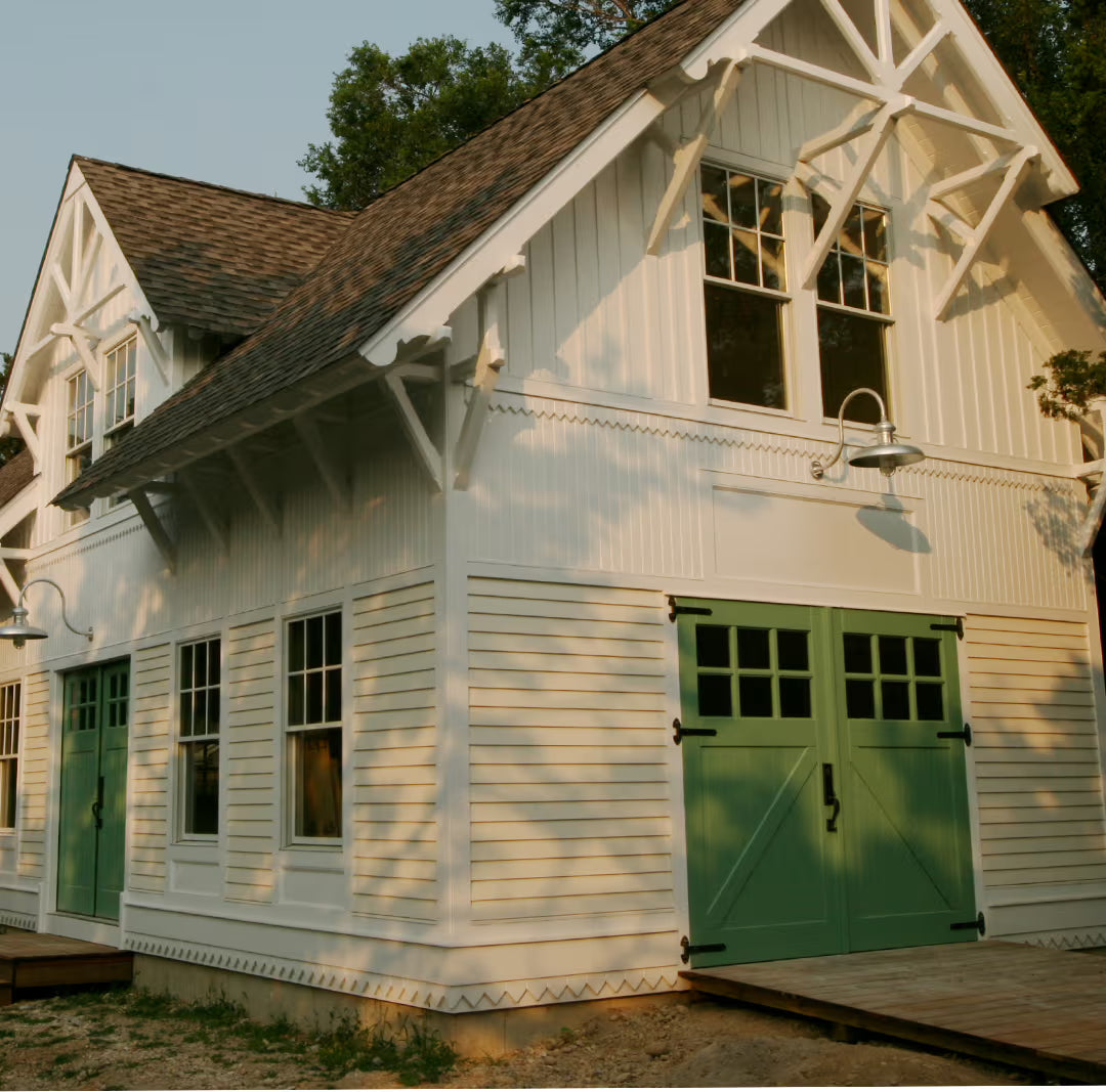 Green Z-brace carriage garage door installed on a residential exterior, shown in daylight with traditional plank detailing.
