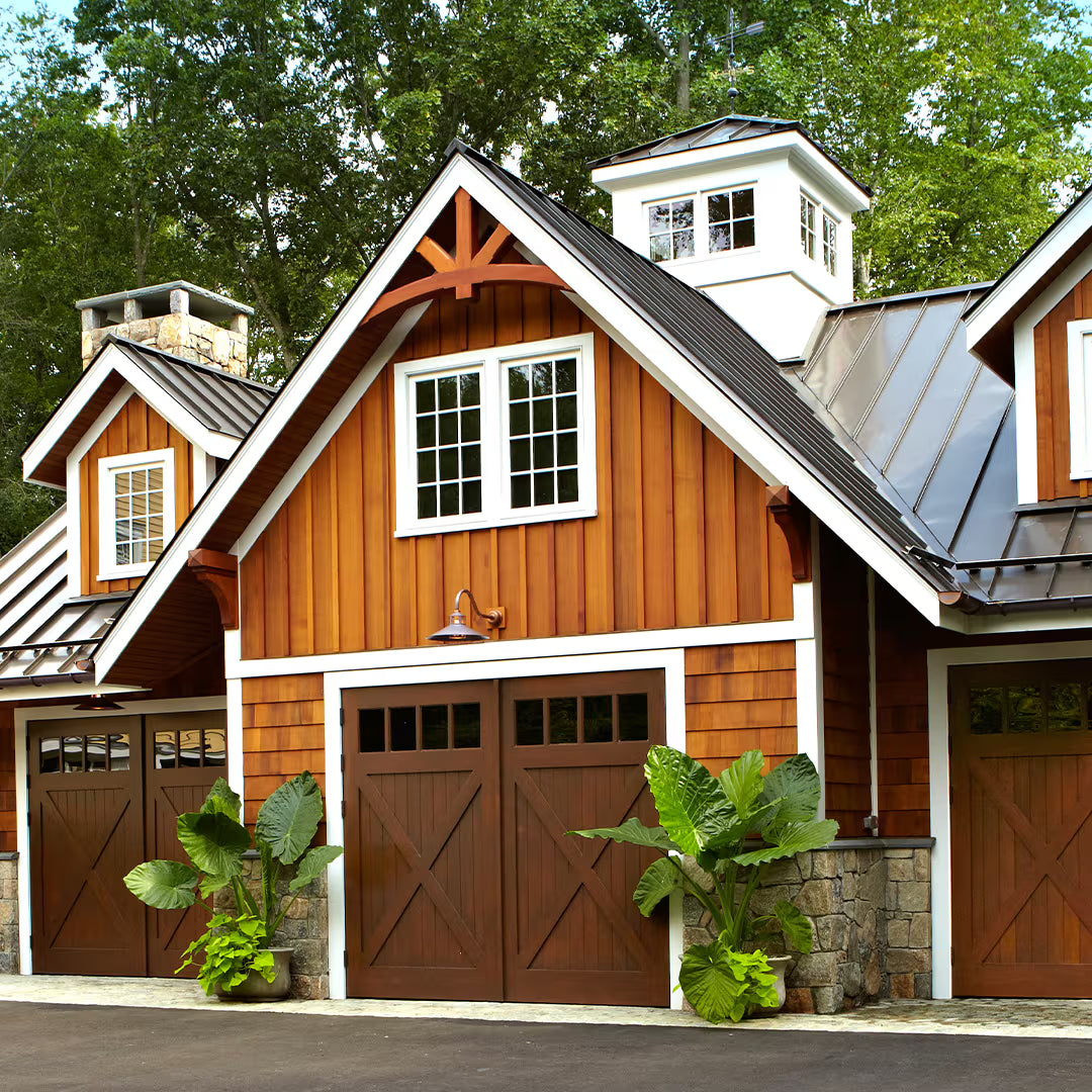 Carriage garage door with X-brace detailing and clear window panels, installed on a residential exterior in natural daylight.