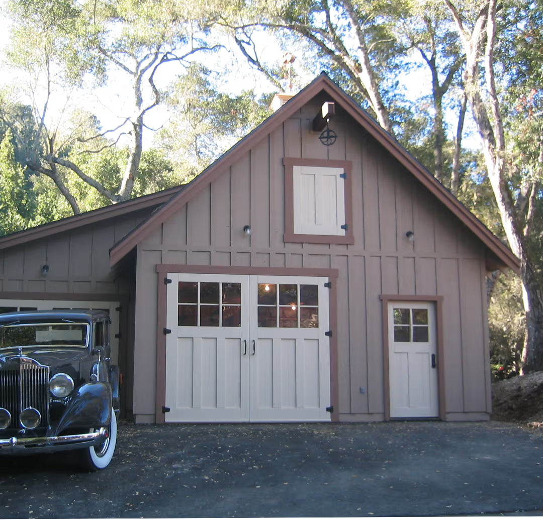 Beige Craftsman-style carriage garage door with a matching entry door, shown on a residential exterior in natural daylight.