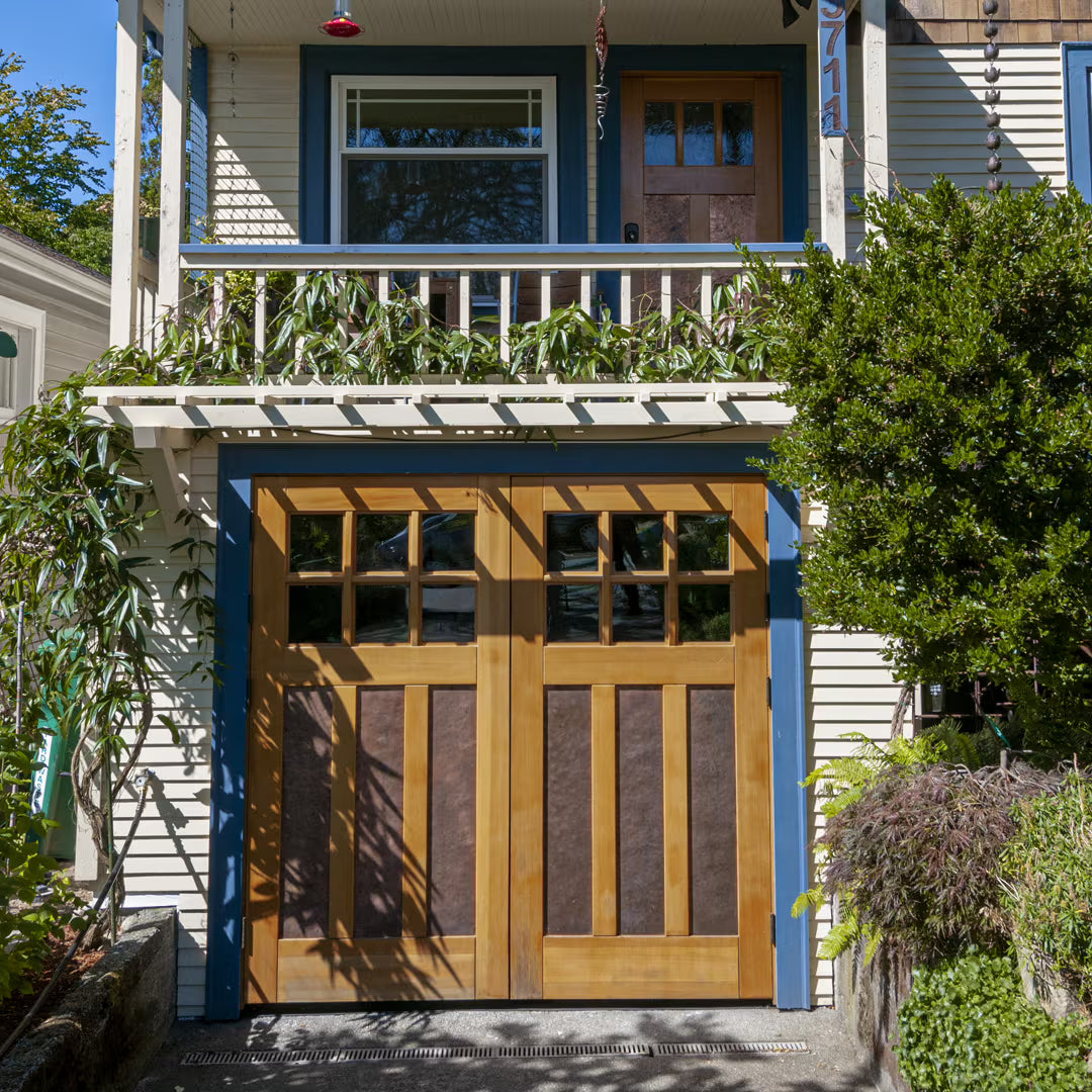 Craftsman-style carriage garage door with galvanized metal panels, installed on a residential exterior in daylight.