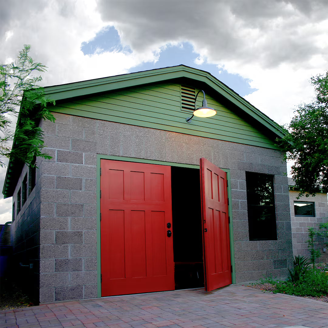 Red Craftsman-style carriage garage door installed on a residential exterior, shown in daylight with traditional panel detailing.