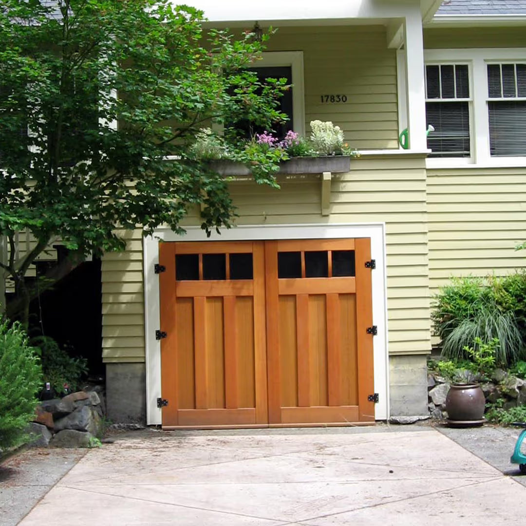 Carriage garage door with a classic mid-brace design, installed on a residential exterior in natural daylight.