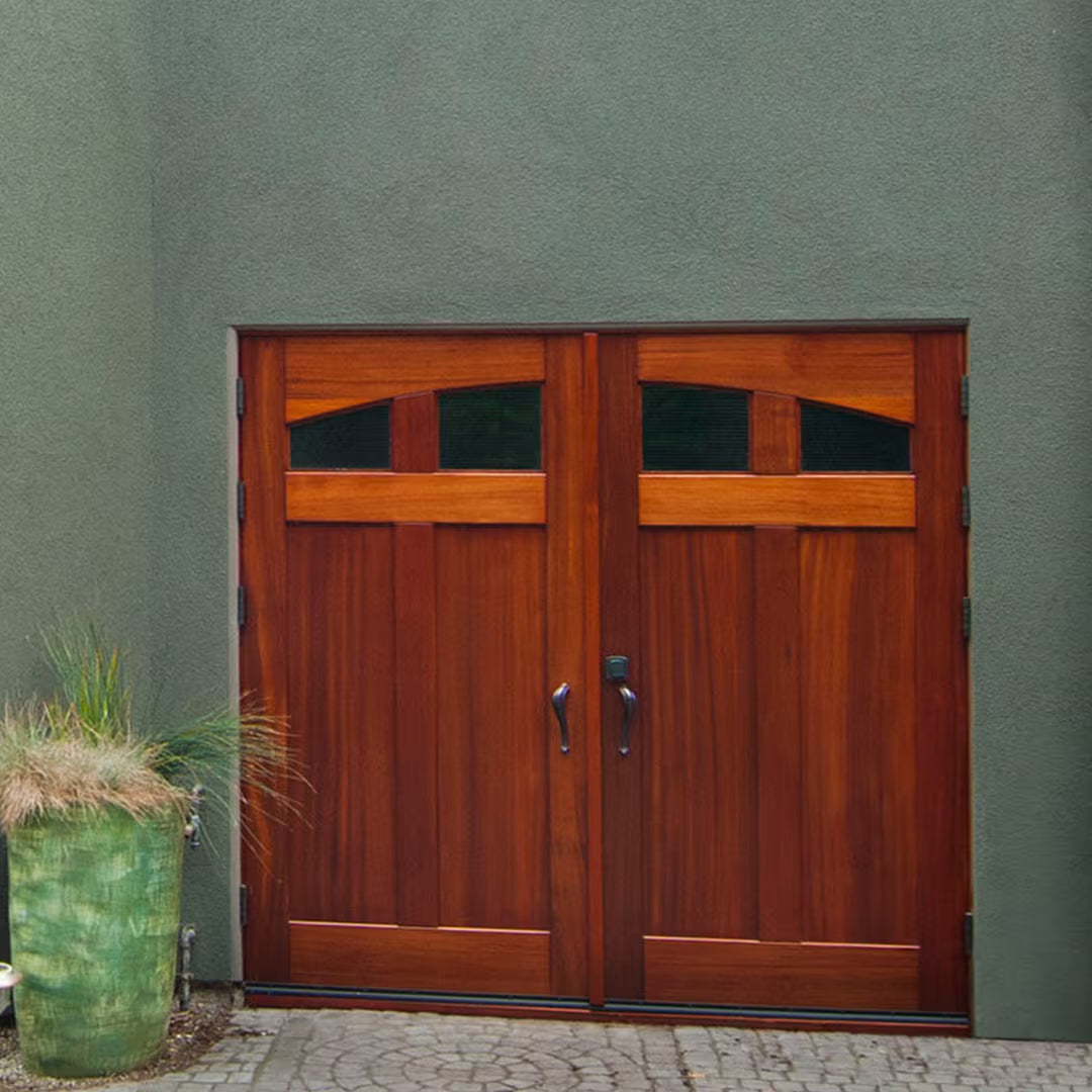 Craftsman-style carriage garage door with arched glass panels, installed on a residential exterior in natural daylight.