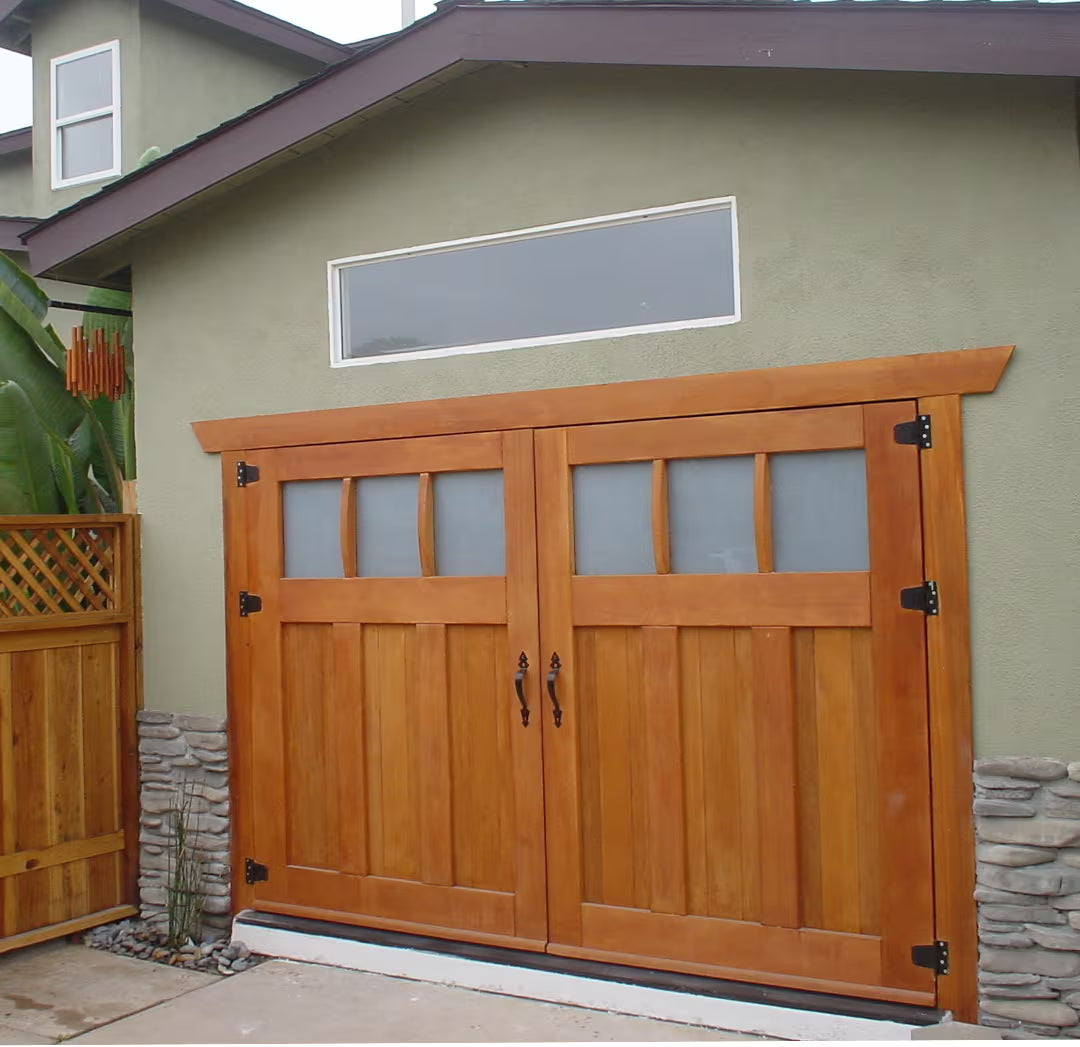 Craftsman-style carriage garage door with extended casing, installed on a residential exterior in natural daylight.