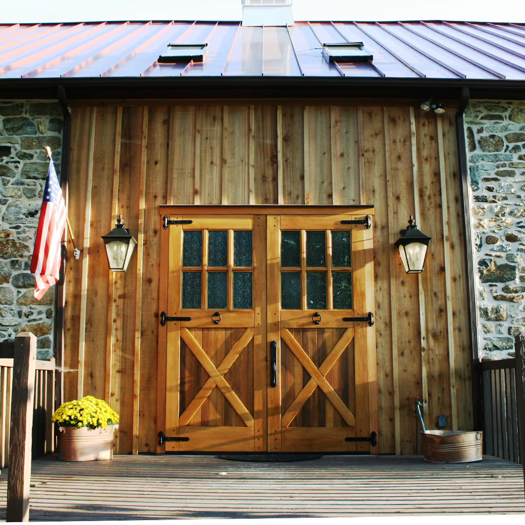 Carriage garage door with an X-brace design, privacy glass panels, and medium decorative hinges, installed on a residential exterior in natural daylight.