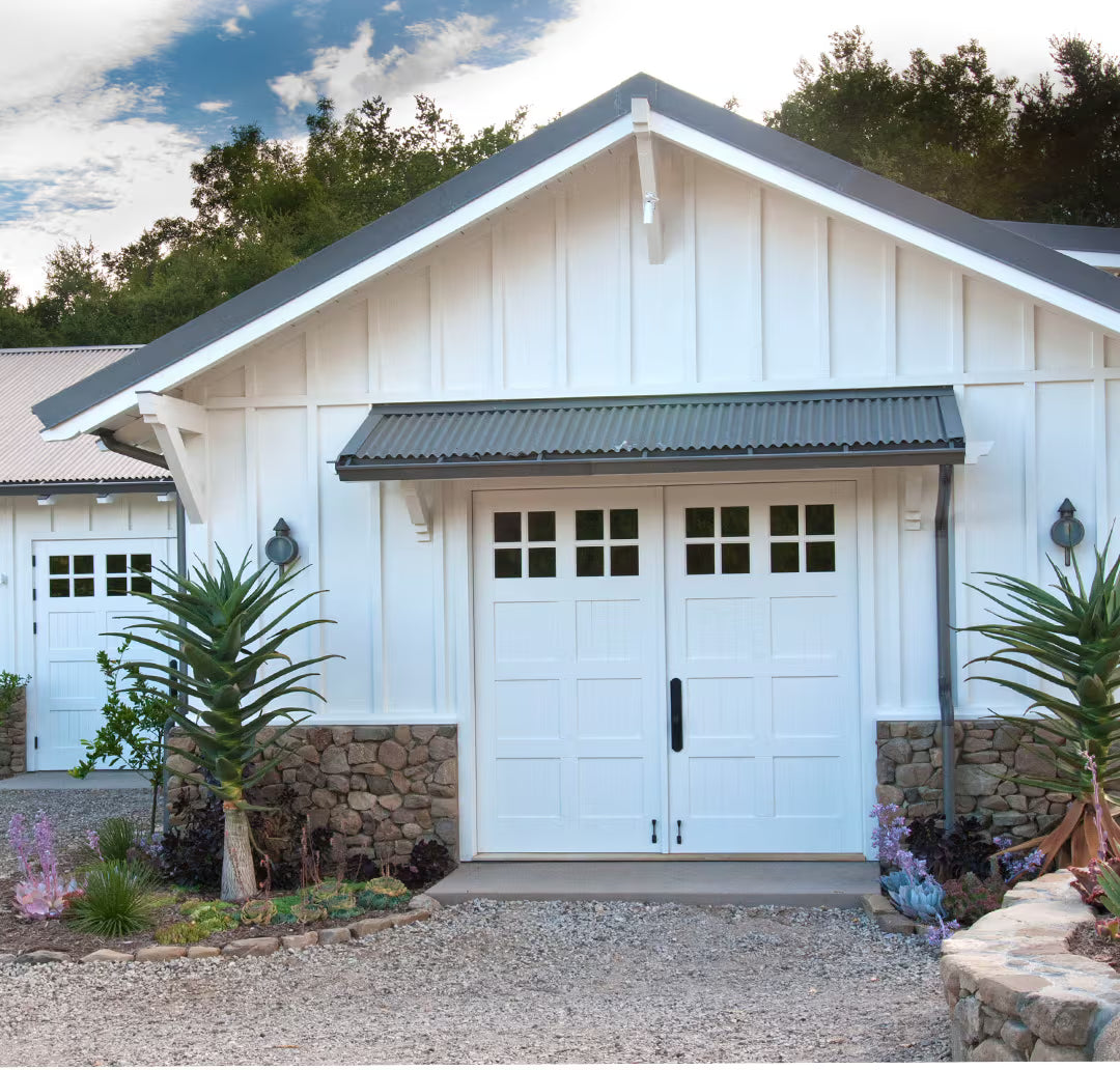White carriage garage door with a square brace design, installed on a residential exterior in natural daylight.