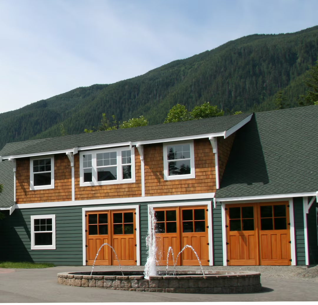 Two-story house with wooden carriage doors doors and a mountain in the background