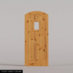 Modena arched door in Tight Knot Cedar, with vertical wood planks and a small arched-top window. Labeled wood species view.
