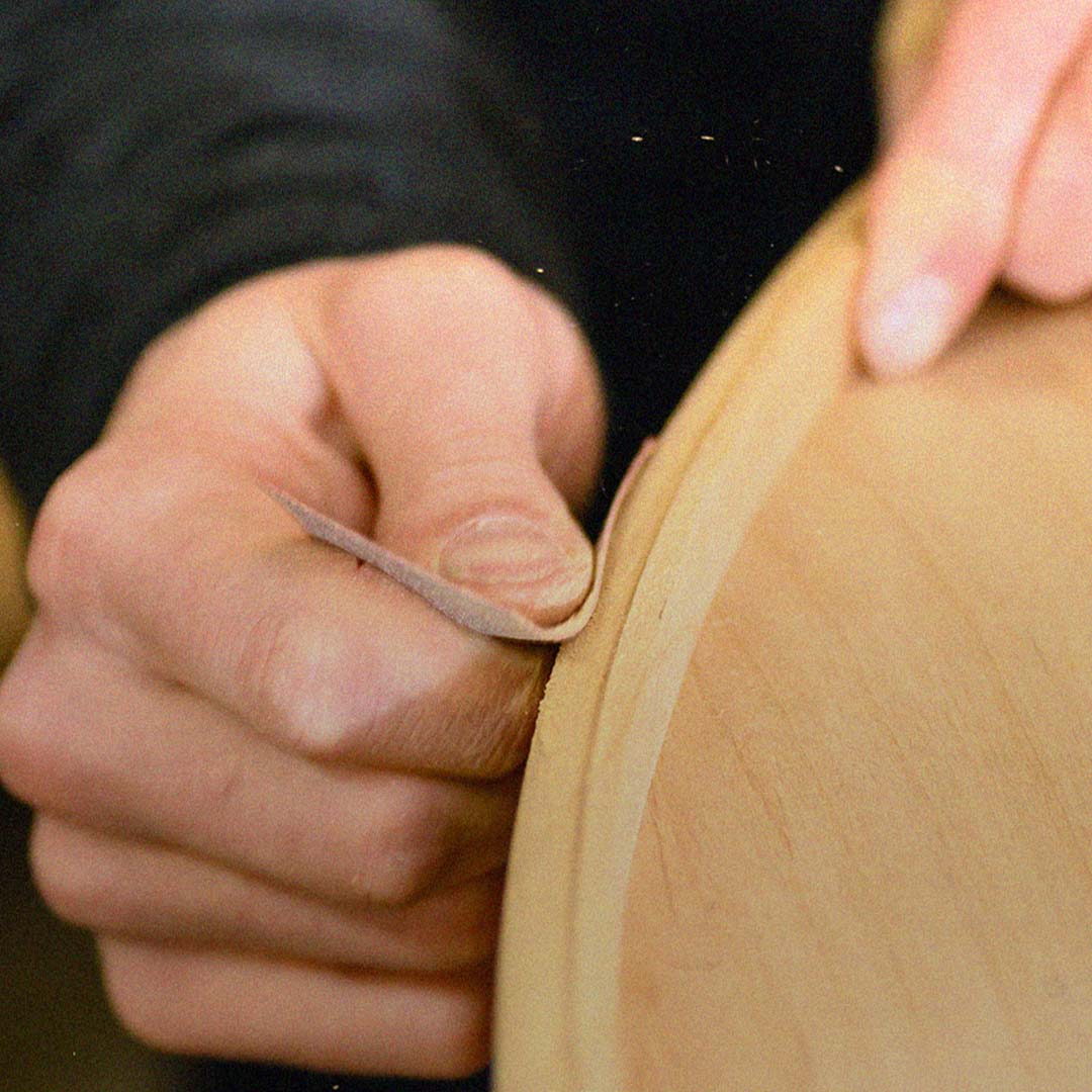Close up of a woodworker's hands sanding a round wooden part of a wood door