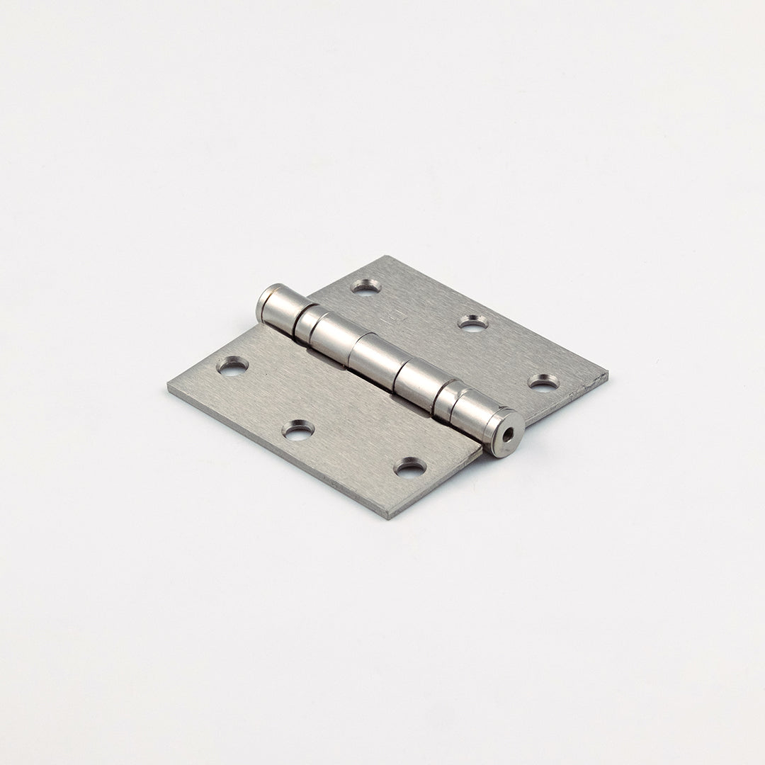 Metallic door hinge on a light pink background