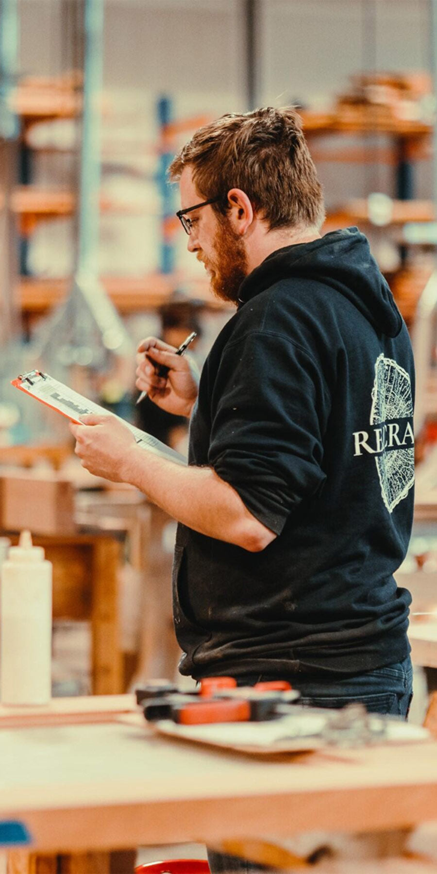 Craftsman holding a clipboard at the woodshop.