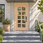RealCraft Padua Maple arched entry door with ten glass lites at a New York-inspired pale-brick townhouse stoop with a green steel railing.