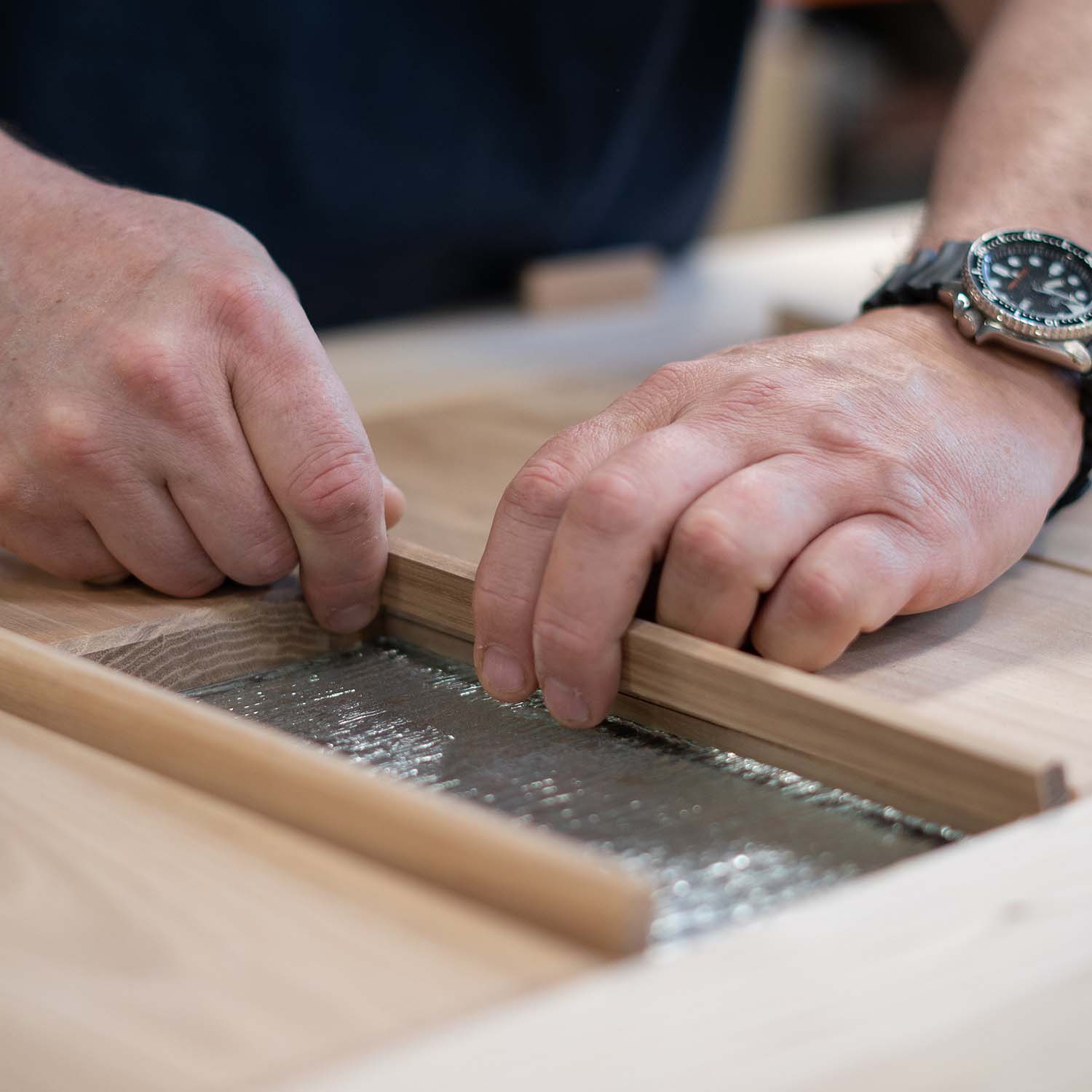 Craftsman's inserting a glass pane on a wooden door.