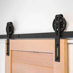 Black Big Spoke Wheel Barn Door Hardware installed on a beach wood door