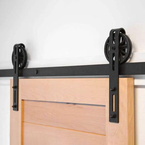 Black Big Spoke Wheel Barn Door Hardware installed on a beach wood door