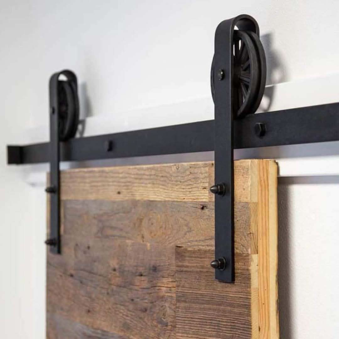 Black Big Spoke Wheel Barn Door Hardware installed on a reclaimed wood door